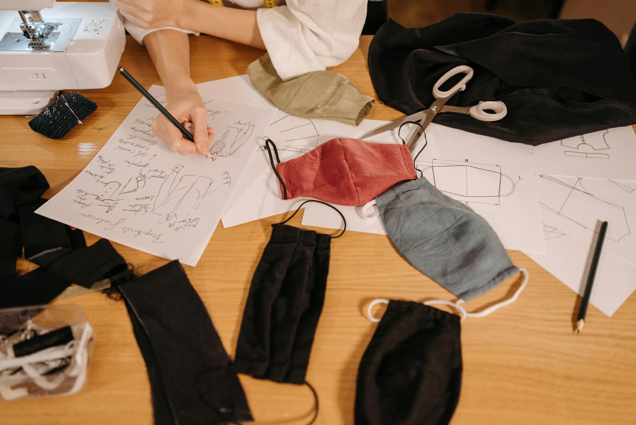 Hands-on sewing workspace featuring sketches, masks, and a sewing machine.