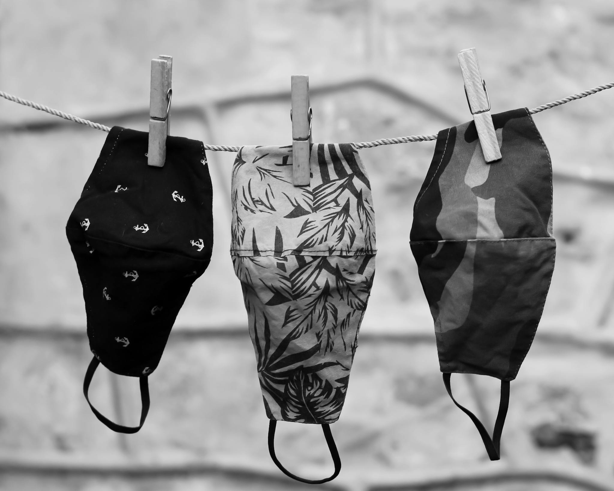 Three stylish face masks hanging on a clothesline, showcasing different patterns.